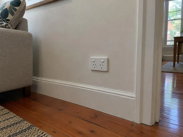 Double power point on a painted living room wall above timber floorboards in Manly